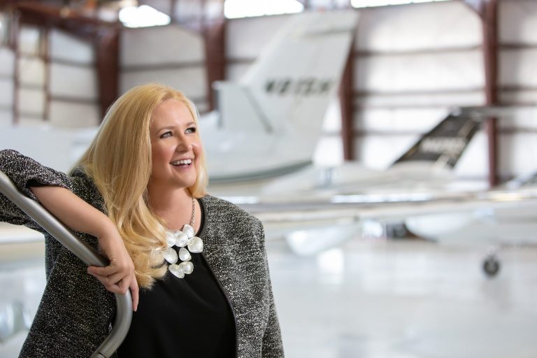 Denise Wilson, CAM, Founder and President of The Jet Agent - standing in hangar in front of private Citation aircraft
